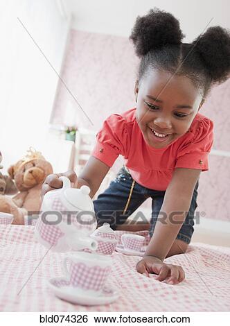 Stock Photograph - African girl having tea party. Fotosearch