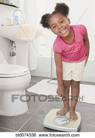 Stock Photograph - African girl weight herself. Fotosearch