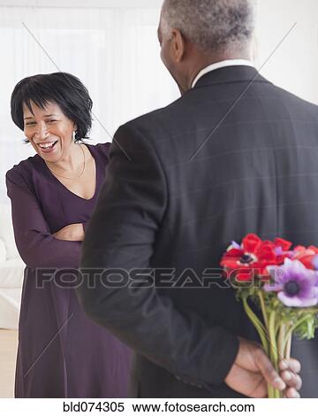 Stock Photography - African man bringing wife flowers. Fotosearch