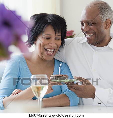 Stock Photo - African man giving wife birthday cupcake. Fotosearch