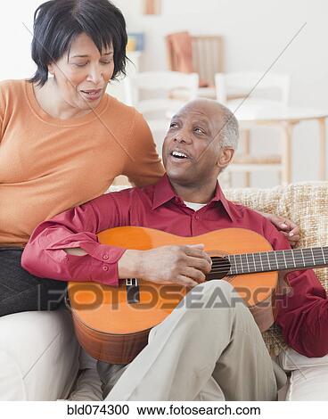 Stock Image - African man playing guitar for wife. Fotosearch