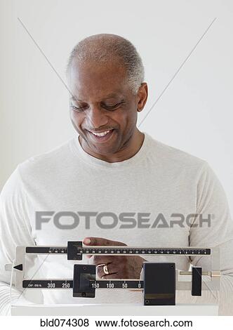 Stock Photo - African man weighing himself. Fotosearch