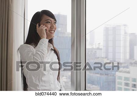 Stock Image - Asian businesswoman talking on cell phone. Fotosearch