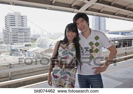 Stock Image - Asian couple hugging on subway platform. Fotosearch