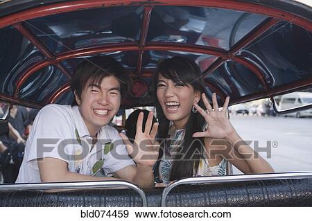 Stock Photo - Asian couple in taxi waving. Fotosearch