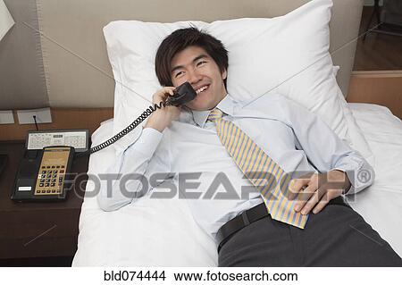 Picture - Chinese businessman on telephone in hotel room. Fotosearch