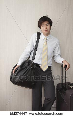 Stock Photo - Chinese businessman standing with luggage. Fotosearch