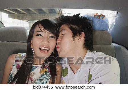 Stock Photography - Chinese man kissing girlfriend in back of car. Fotosearch