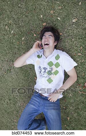 Stock Image - Chinese man laughing and using cell phone. Fotosearch