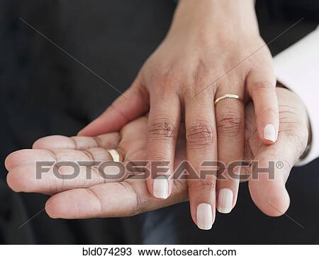 Stock Image - Close up of African couple holding hands. Fotosearch