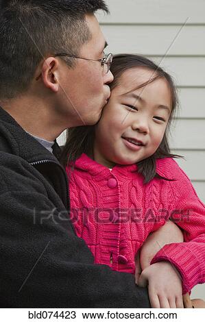 Stock Image - Korean father kissing daughter. Fotosearch