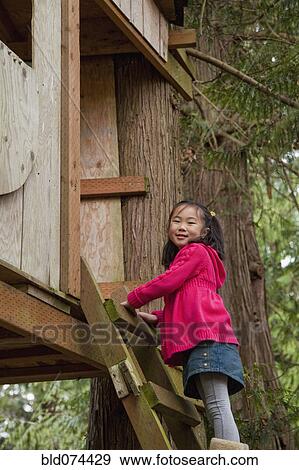 Stock Photo - Korean girl climbing into tree house. Fotosearch