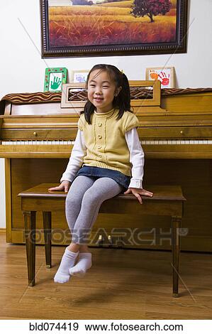 Stock Photo - Korean girl sitting on piano bench. Fotosearch