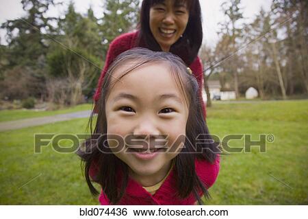 Stock Photograph - Korean mother playing outdoors with daughter. Fotosearch