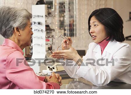 Korean optician showing eyeglasses to customer View Large Photo Image Stock Image - Korean optician showing eyeglasses to customer. Fotosearch