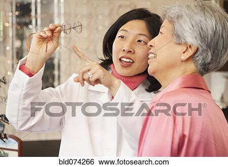 Korean optician showing eyeglasses to customer View Large Photo Image Stock Photograph - Korean optician showing eyeglasses to customer. Fotosearch