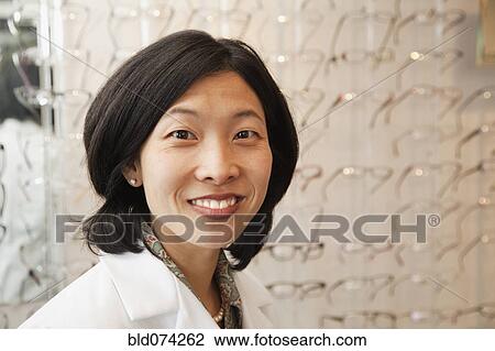 Stock Image - Korean optician standing in store. Fotosearch
