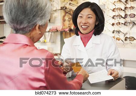 Stock Image - Korean optician talking to customer. Fotosearch