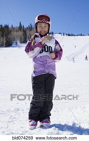 Stock Photo - Mixed race girl showing off skiing medal. Fotosearch