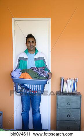 Stock Image - Mixed race man carrying laundry basket. Fotosearch