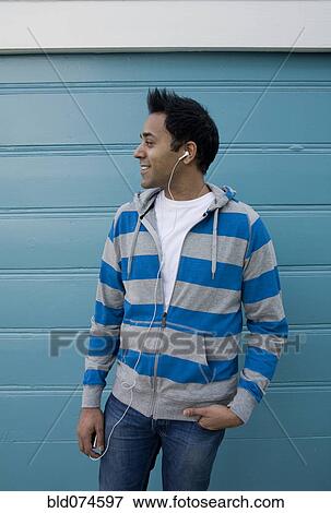Stock Photo - Mixed race man listening to headphones. Fotosearch