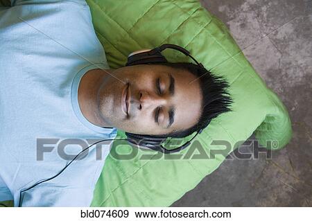 Stock Photo - Mixed race man listening to headphones. Fotosearch