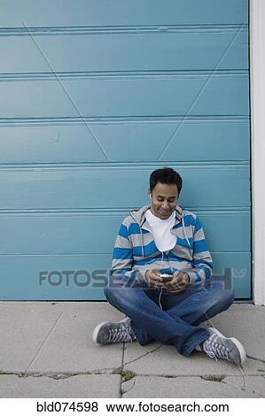 Stock Photo - Mixed race man listening to mp3 player. Fotosearch