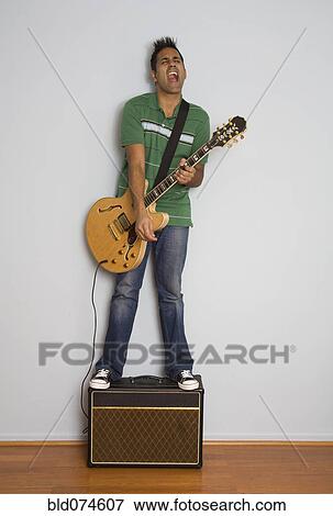 Stock Photo - Mixed race man playing electric guitar. Fotosearch