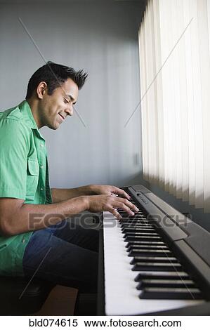 Stock Photography - Mixed race man playing electric keyboard. Fotosearch