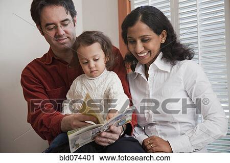 Stock Image - Parents reading book to daughter. Fotosearch