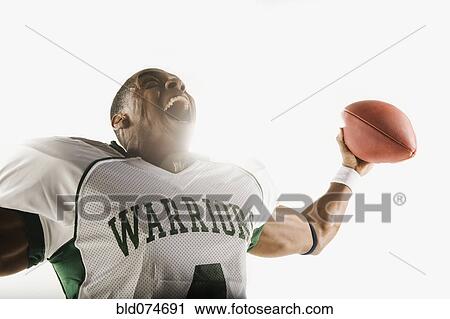 Stock Image - African football player holding football and celebrating. Fotosearch