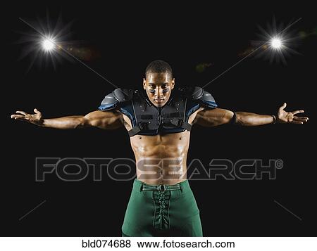 Stock Photo - African football player wearing protective pads with arms outstretched. Fotosearch