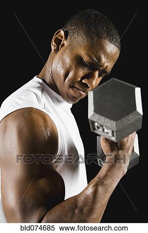 Stock Photography - African man doing biceps curl with dumbbell. Fotosearch