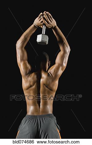 Stock Photograph - African man doing triceps extensions with dumbbell. Fotosearch