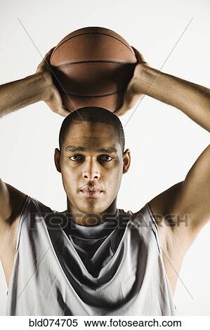 Stock Photography - African man holding basketball overhead. Fotosearch