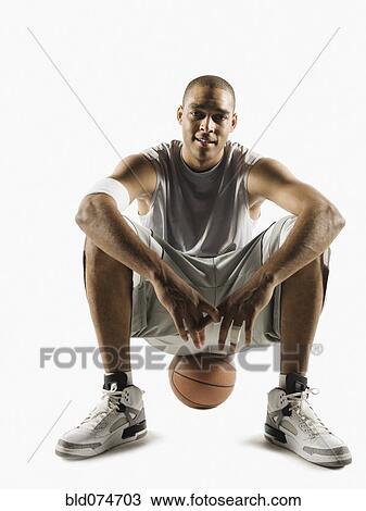 Stock Image - African man sitting on basketball. Fotosearch