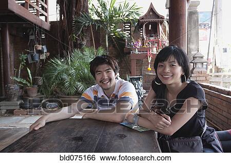 Asian couple sitting at patio table View Large Photo Image Stock Photograph - Asian couple sitting at patio table. Fotosearch