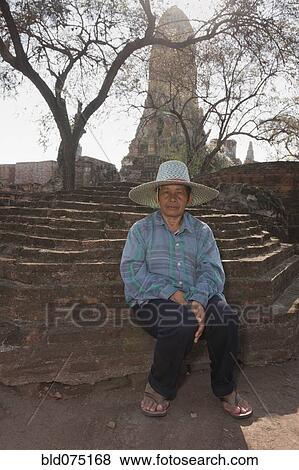 Stock Photo - Asian man sitting outside temple. Fotosearch