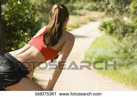 Stock Image - Hispanic runner stretching on path. Fotosearch
