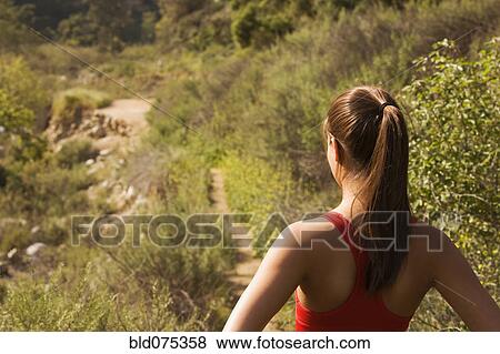 Stock Photo - Hispanic woman looking at nature trail. Fotosearch