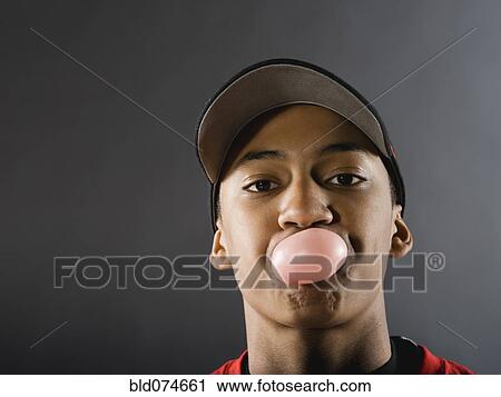 Stock Image - Mixed race baseball player blowing bubble with gum. Fotosearch