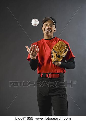Stock Photography - Mixed race baseball player tossing baseball. Fotosearch