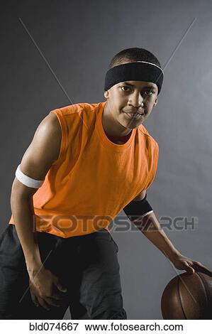 Stock Photo - Mixed race basketball player dribbling basketball. Fotosearch