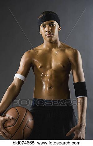 Stock Photography - Mixed race basketball player holding ball. Fotosearch