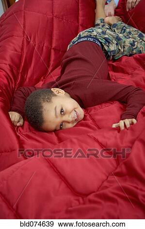 Stock Photo - Mixed race boy laying in bed. Fotosearch