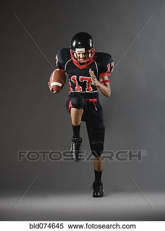 Stock Photography - Mixed race football player running with football. Fotosearch