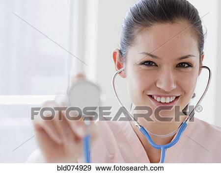 Stock Photo - Mixed race nurse holding stethoscope. Fotosearch