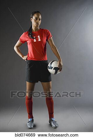 Stock Photo - Mixed race soccer player holding soccer ball. Fotosearch