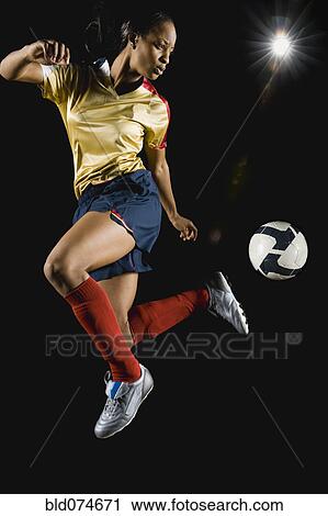 Mixed race soccer player kicking ball in mid-air View Large Photo Image Stock Image - Mixed race soccer player kicking ball in mid-air. Fotosearch
