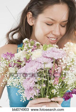 Stock Image - Mixed race woman holding bouquet of flowers. Fotosearch